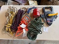 All items laid out: tape measure, three ropes, work light, green extension cord, spray tool