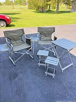 Group view of two folding chairs, one larger folding table and two smaller folding stools