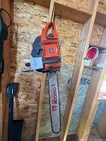 Full view of Husqvarna 61 chainsaw hanging on stud wall