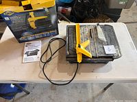 Tile saw with attached power cord, extension table and guide on workbench