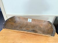 Full view of wooden trough on table showing size and interior wear