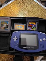 Game Boy Advance console with three cartridges in carrying case interior