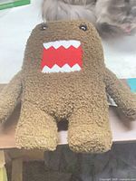 Front view of brown Domo plush showing red mouth and teeth