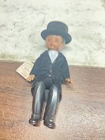 Full view of 6-inch Madame Alexander doll in black formal outfit and top hat