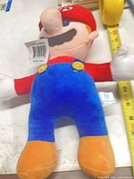 Front view of Mario plush showing size, colors, buttons, tags