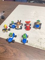 Seven Nintendo Mario Kart toy cars laid out on table