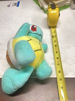 Full view of Squirtle plush alongside tape measure indicating roughly 10 inches