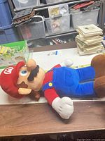 Full body side view of Mario plush on table next to ruler