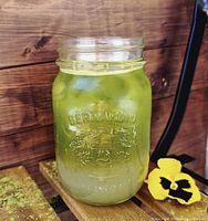 Green iced beverage in branded mason jar