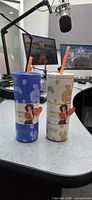 Blue and cream cow print insulated bottles with straws on desk