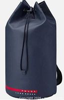 Front three-quarter view of cylindrical Prada Luna Rossa Ocean sailing bag showing drawstring top, strap and branding
