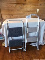 Both folding step stools side by side, black-tread stool folded, aluminum-tread stool open