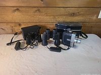 Full lot showing camera, binoculars, both cases, lens cap and straps