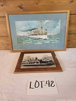 Both framed pieces on table: battleship print above, ferry photograph below