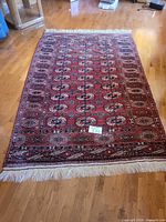 Full view of rectangular red Bokhara-style wool rug with fringe