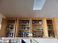 Upper wall cabinets open showing multiple blue Maxwell House tins and plastic tubs