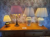 All four table lamps with shades on wooden console