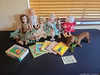 Group shot showing all dolls, plush dachshund, Paddington books, boxed item