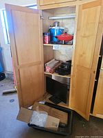 Cabinet overview with monitor, boxed items, cookware, and appliances visible