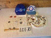 Full lot showing two caps, towel with pins, sun hat with pins and lot number card