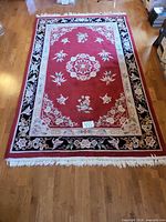Full view of red oriental rug on hardwood floor showing pattern and size