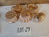 All six copper gelatin molds grouped, showing varied shapes