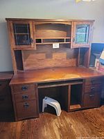 Full frontal view of desk and hutch showing glass doors, open shelving, drawers and knee space