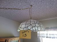 Full view of pendant light hanging from ceiling via brass chain