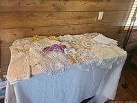 Overview of assorted crochet and lace linens spread on table