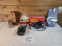 Group shot of all five items showing boxes, iron, heating pad, blood pressure kit, ice bag and ironing board pad