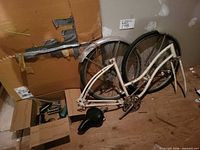 disassembled bicycle frame, two wheels, fenders, saddle and box of parts