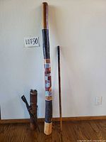 Full view of didgeridoo, cylindrical tube, and beater stick