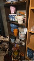 Tall shelving unit filled with various ceramic planters, terracotta pots and wrought iron holders