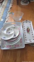 Group shot showing stacked trays, divided dish, glass bowl, long floral platters