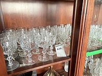 Shelf displaying numerous clear cut crystal goblets of two styles