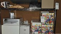 Shelving with several boxed wine glass sets including illustrated cartons, plain white boxes and black branded box