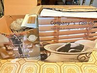 Retail box showing Company's Coming soup tureen on stand, contents including metal stand and glass votive cups visible
