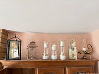Entire assortment on cabinet: two lanterns, three cylindrical vases, rectangular vase, bud vase, brass bowl