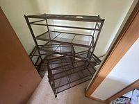 Stacked view of four brown metal folding shelves