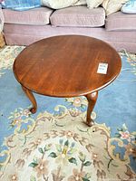 Full view of round cherry coffee table on rug