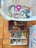 Large laundry basket and drawer trays full of assorted jewelry pieces