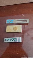 Overview of three money clips: turquoise inlay sterling, gold-filled plain, green inlay sterling