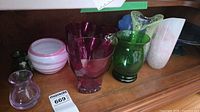 Group view of multiple glass vases and bowls on shelf