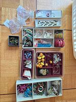 Overview of all trays showing assorted bracelets, necklaces, earrings, charms in boxes