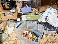 Shelf with boxed Ergo clock, Cheese Keeper, Trio set, storage tote and other items