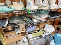 Shelf view showing turquoise serving pieces, plastic bin with cards, additional lot contents