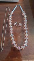All pieces laid out: bead necklace, earrings, silver chain