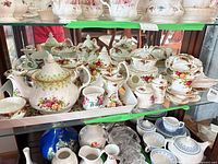 Shelved group showing teapot, creamer, sugar bowl, multiple cups, saucers and trays