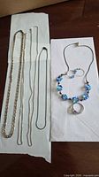All necklaces, beaded set, ring and earrings laid out on white paper
