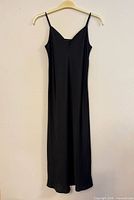 Front view of black ankle-length slip dress on hanger